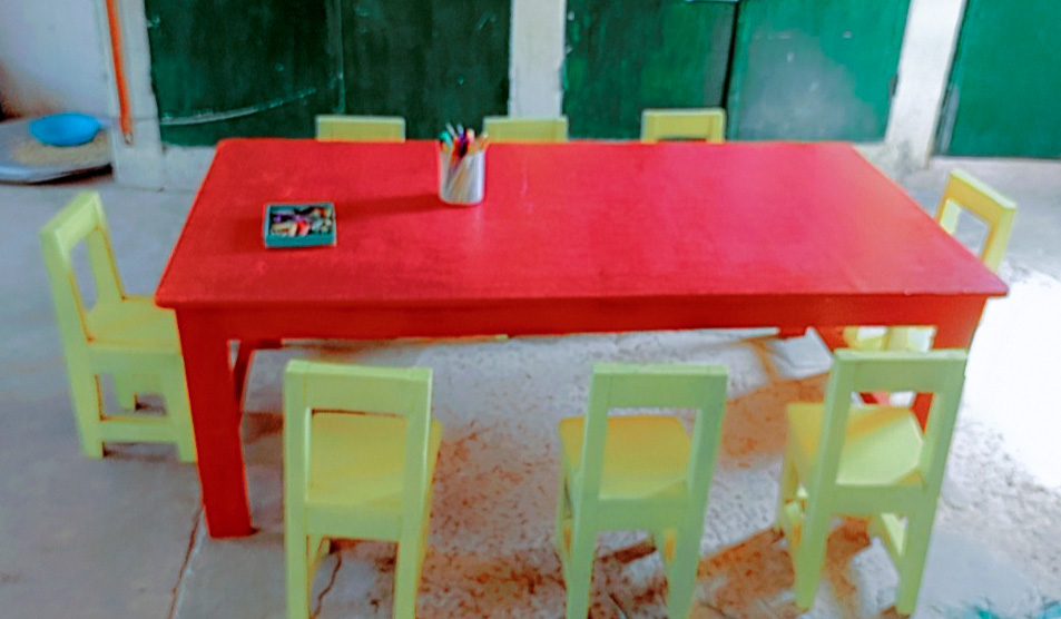 Une grande table rouge et 8 chaises jaunes pour les élèves.