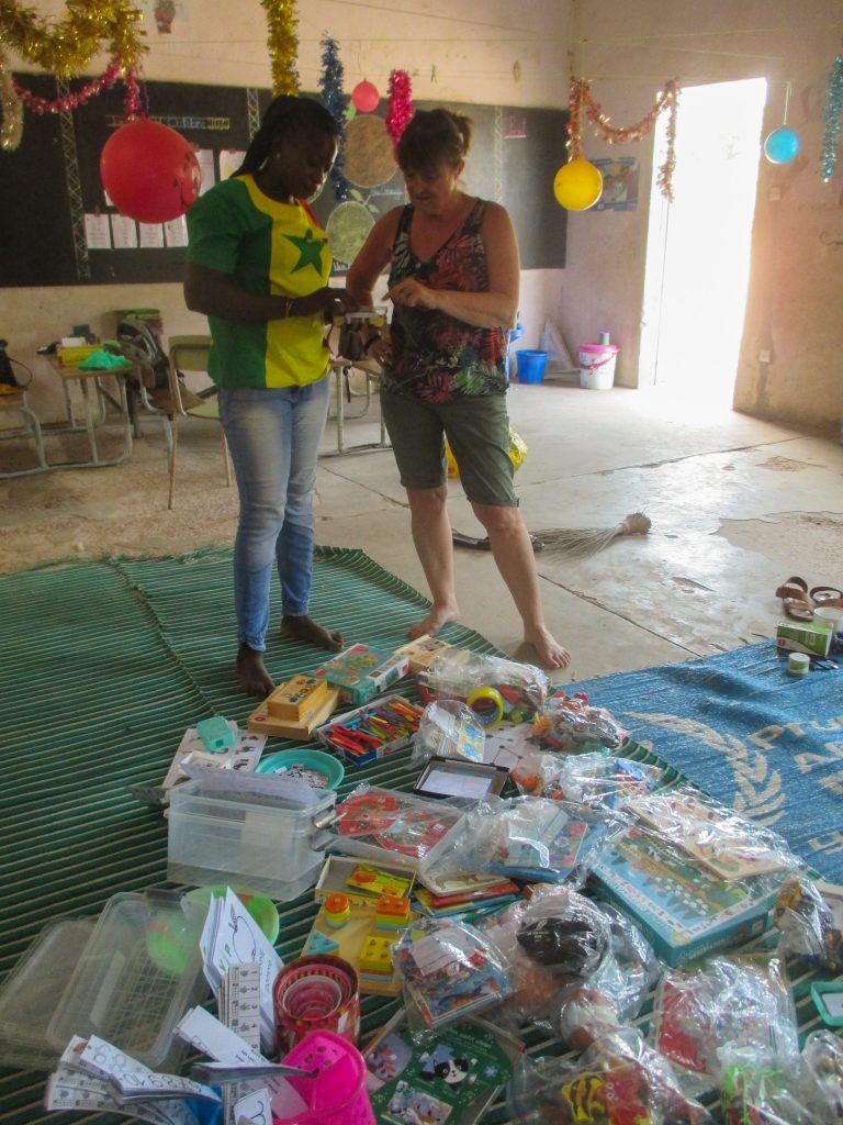 Déballage des sacs remplis de jeux éducatifs par un membre de l'association et de l'équipe pédagogique.